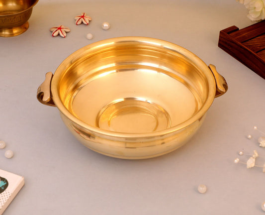 brass urli with handles on a light gray surface