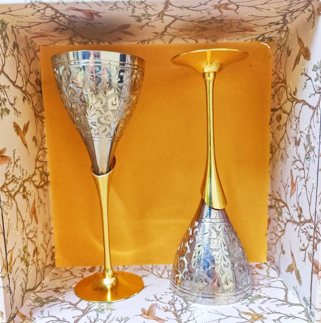 Pair of tall engraved brass wine glasses displayed elegantly on a patterned surface, reflecting the luxury feel of the Spice & Sip Luxe Hamper.