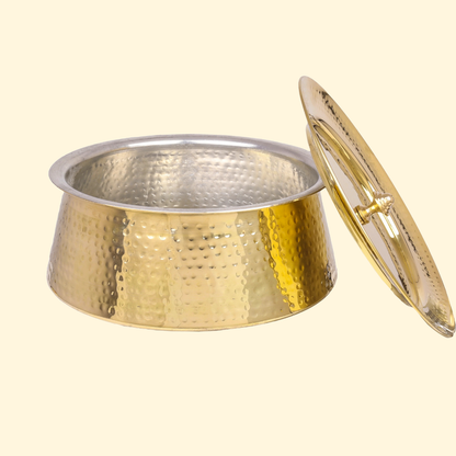 Close-up of the empty Bulkysanta Brass Handi (Hammered Brass Pot, Degchi, Patila) with the lid resting on the side. The vessel features a bright, hammered brass exterior and a contrasting, silver-colored metal lining on the interior, ready for serving food.