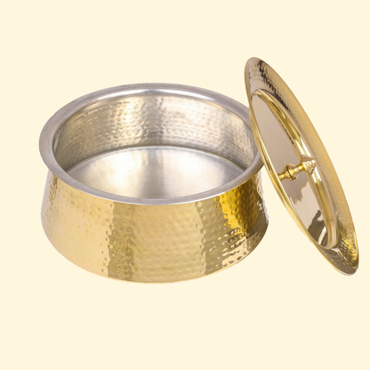 A close-up of the empty Bulkysanta Hammered Brass Handi/Degchi with its lid resting on the side. The interior of the brass pot is lined with a silver-colored metal (likely tin or stainless steel) for safe cooking and serving, and the exterior features a distinct hammered texture.