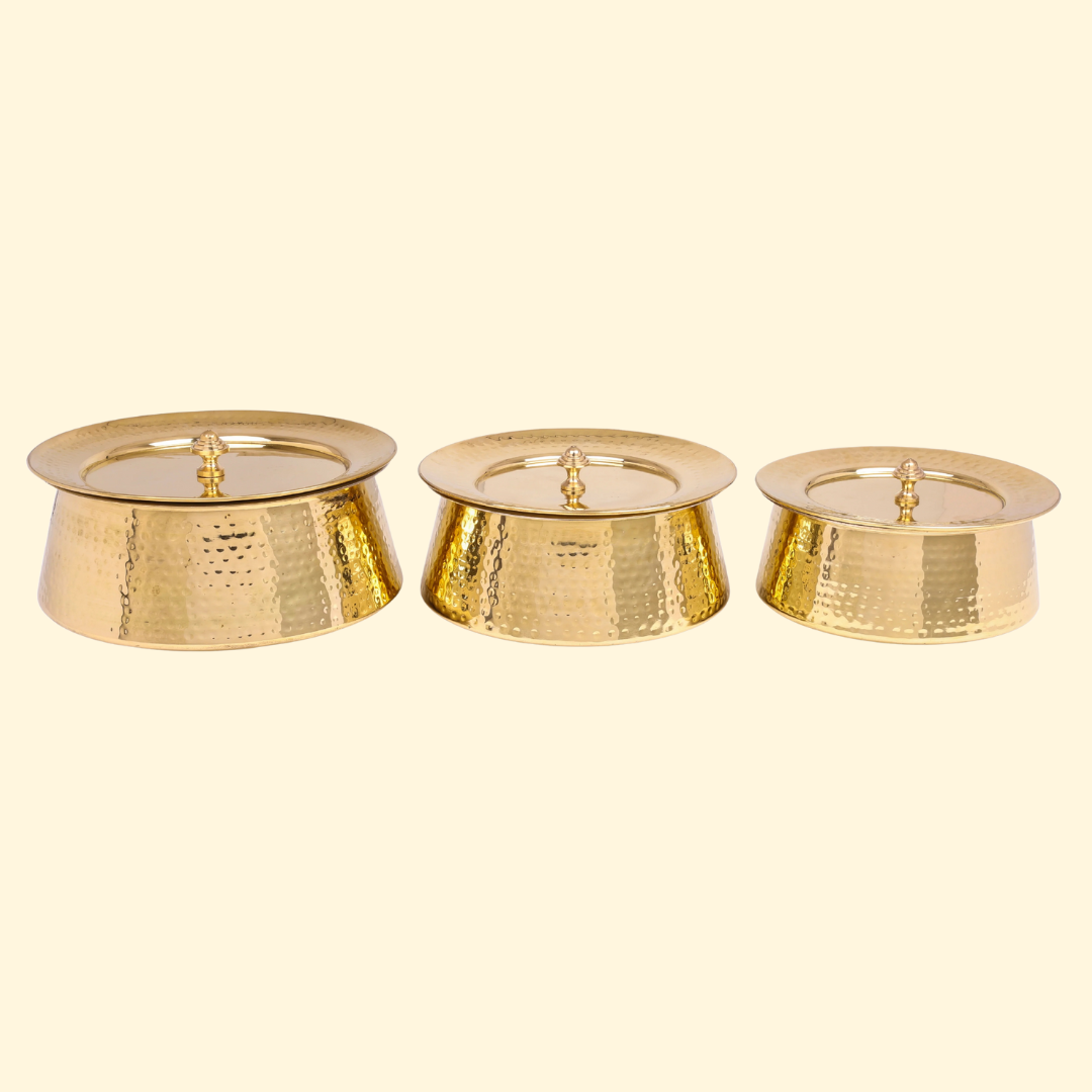 Set of three Bulkysanta hammered brass handis, each with its lid on. The pots are gold-colored and feature a textured, hammered finish.