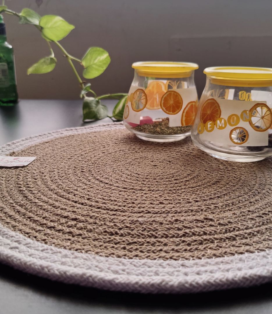 Two glass jars with decorative labels on a textured round placement color white beige