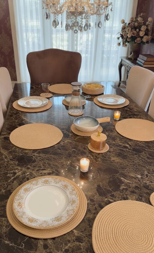 Cozy dining setup with beige woven mats, candles and plates arranged on a dark
table, showcasing elegant dining table mats.