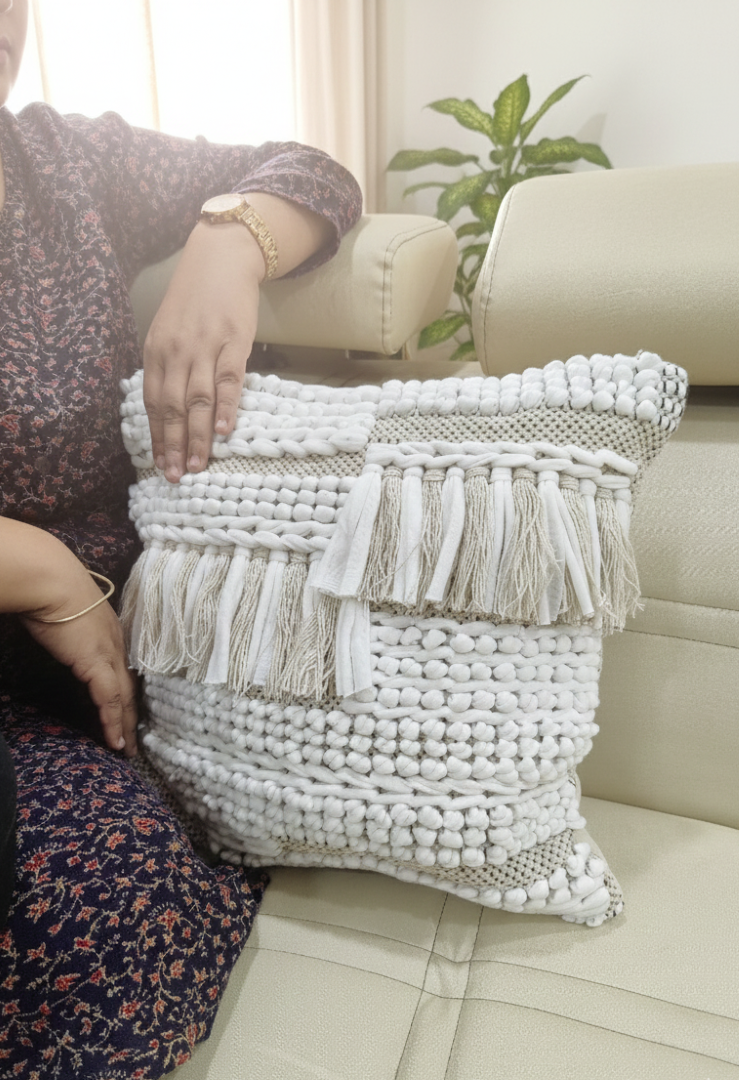 A person seated beside two beige textured cushion covers arranged on the floor.