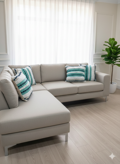 A pair of green and blue stylish cotton cushion covers arranged on a grey sectional sofa.