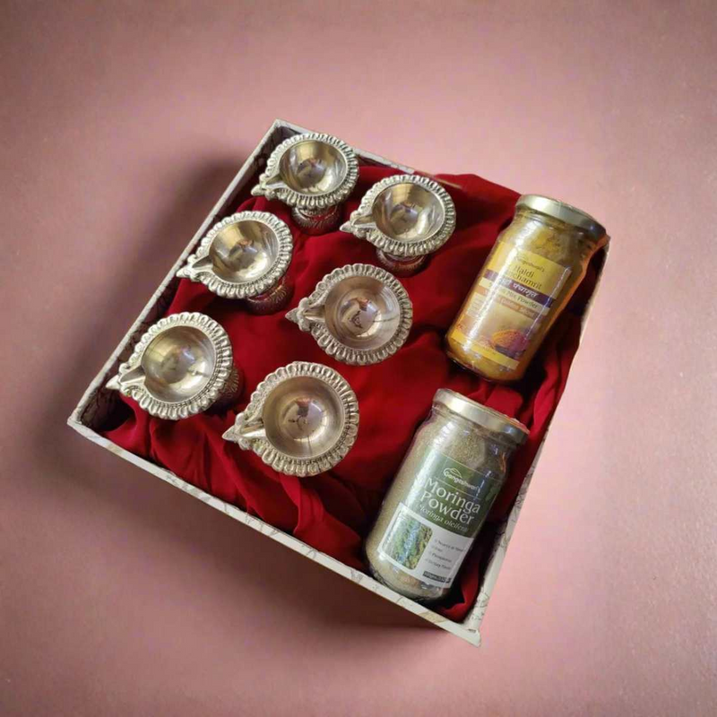 Radiant Ritual Hamper with brass diyas and two natural spice jars arranged in a 
red-lined box, ideal as a premium brass ritual hamper gift set.