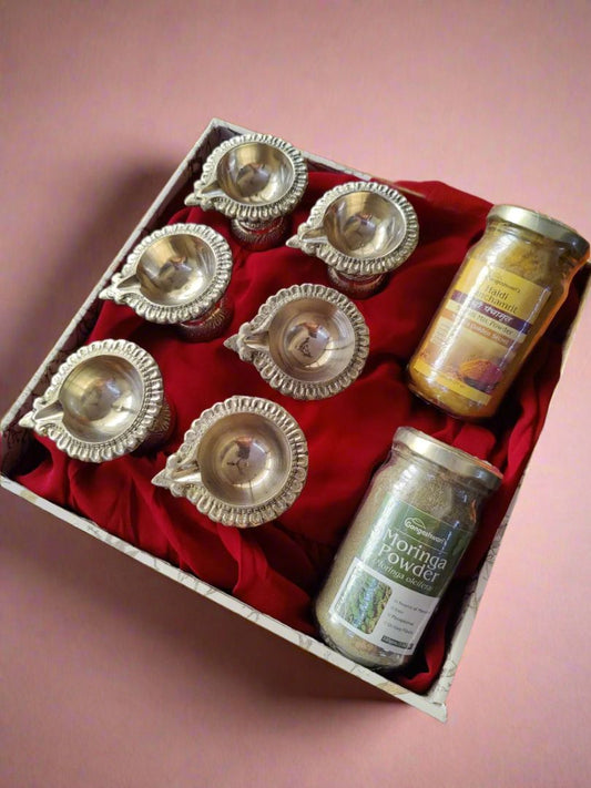 Brass diyas and herbal spice jars beautifully arranged in the Radiant Ritual 
Hamper box, offering an elegant brass gift set for traditional rituals.