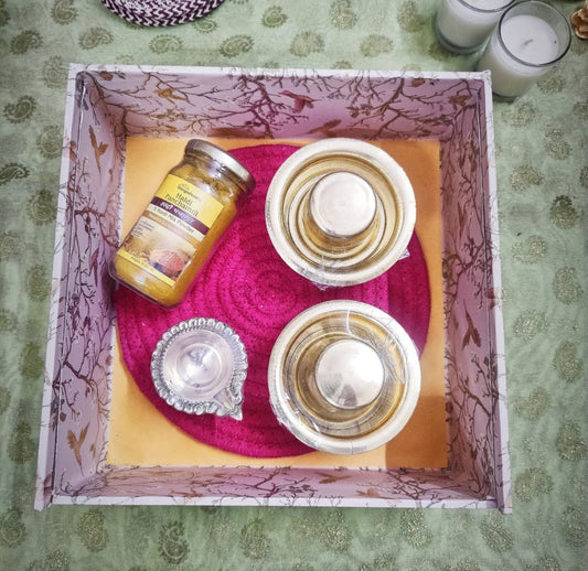 Traditional dabara set with brass bowls, honey jar, and diya placed over green 
filler, forming an elegant brass dabara gift set ideal for cultural gifting rituals.​