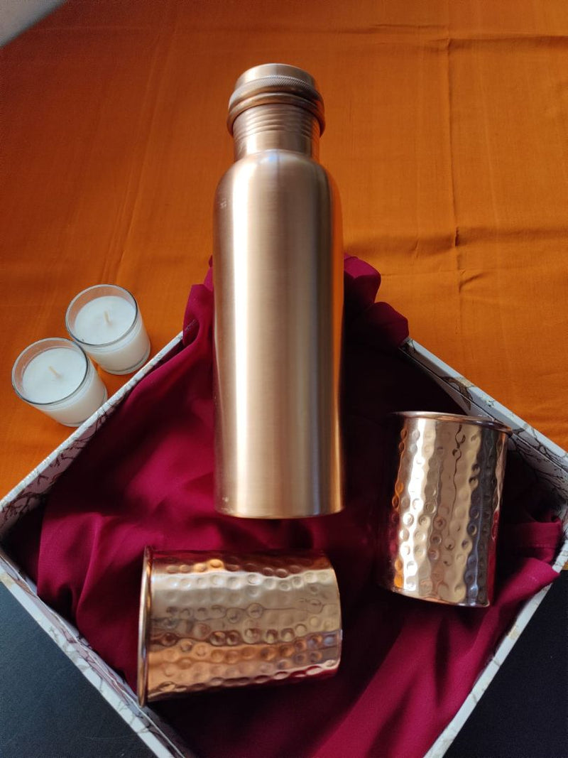 Top-view copper gift set featuring a tall copper bottle and hammered copper 
glasses placed neatly in a gift box, perfect for copper gifts online.
