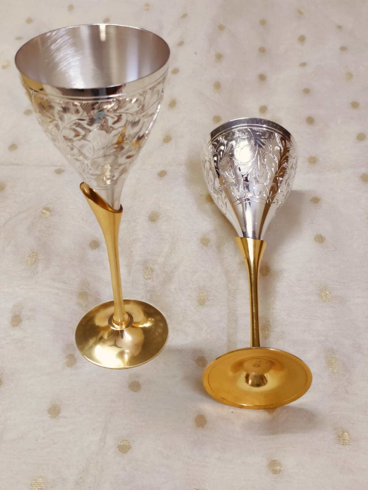 Engraved brass wine glasses with silver finish placed on table