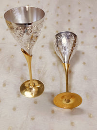 Engraved brass wine glasses with silver finish placed on table