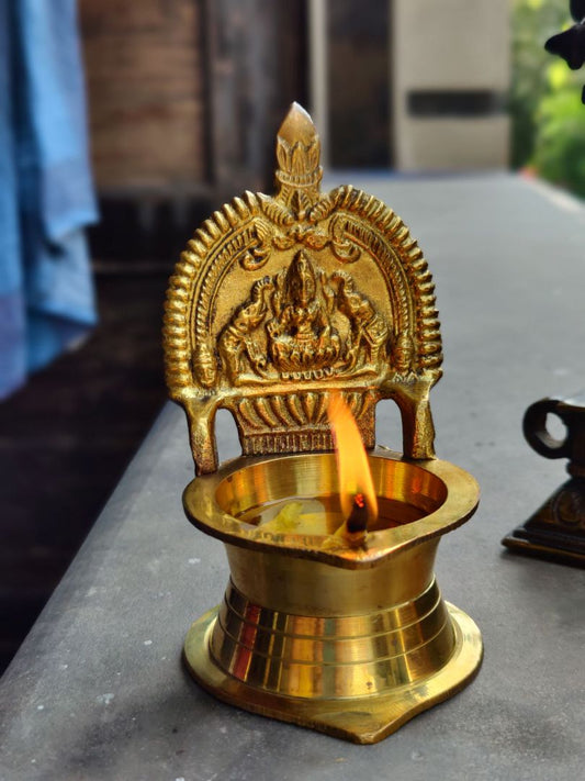 Brass Kamatchi Vilakku displayed on table during puja setup