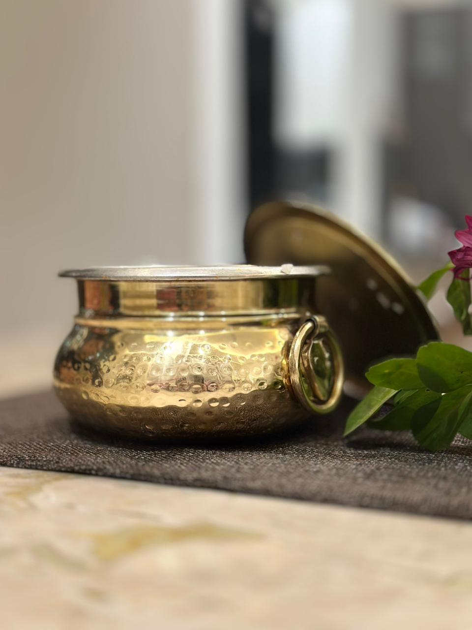 brass container with lid on a textured surface with blurred background
