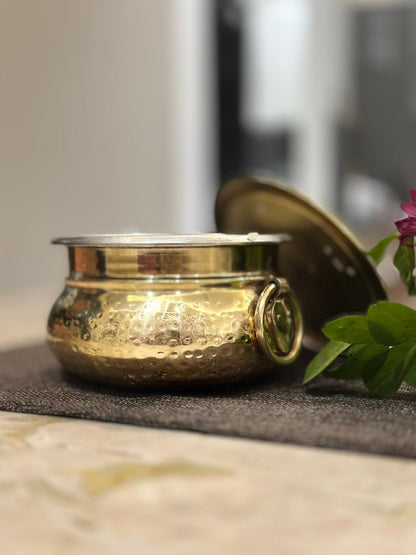 brass container with lid on a textured surface with blurred background