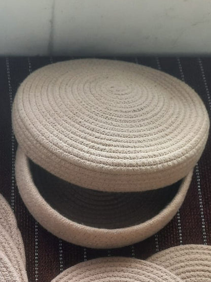 Round woven beige stool on a dark textured surface