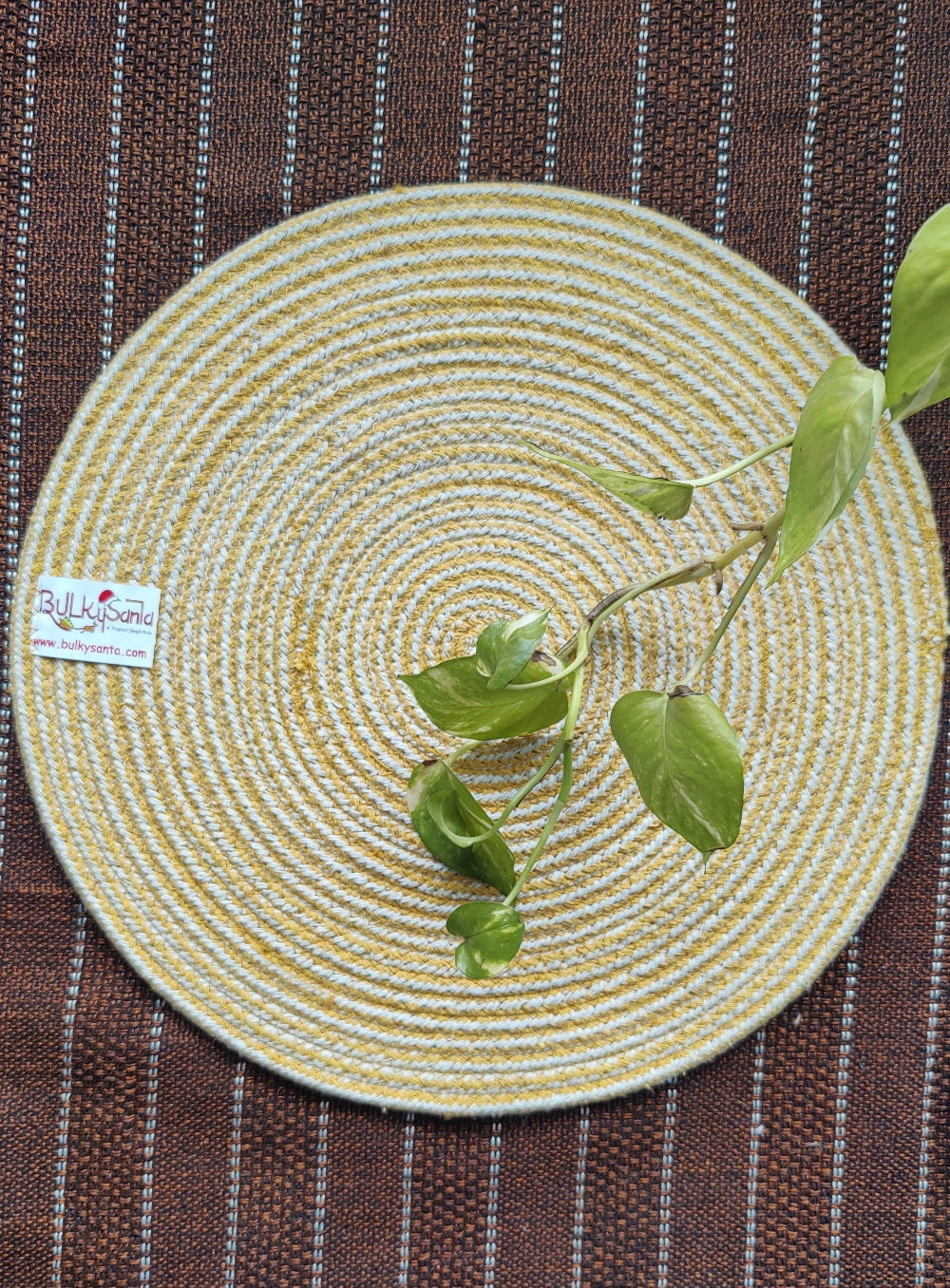 Yellow woven round mat with a green plant stem placed on top, styled naturally
for cotton placemats.