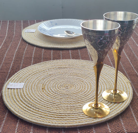 Woven yellow mat set on a brown textured surface beside elegant glassware,
complementing round table mats. Table Mats for 4 seater table, Table mats for 6 seater table, table mats for 8 seater table