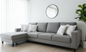 Gray sectional sofa in a living room with a mirror and plant.