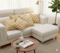 White sectional sofa with yellow patterned cushions in a living room setting.