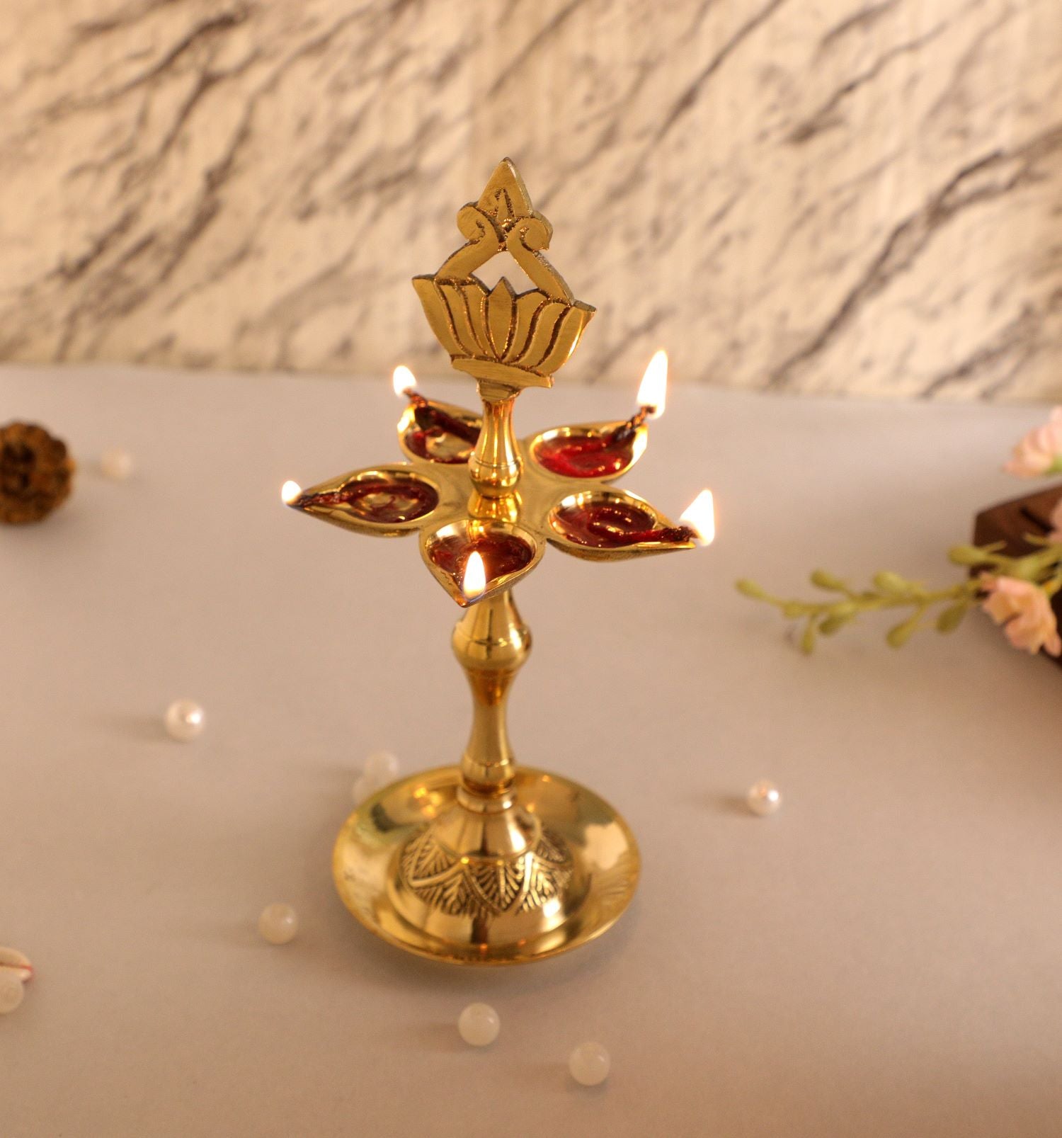 brass oil lamp with four flames on a marble surface