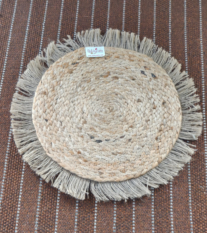 Round woven mat with fringes on a striped fabric background