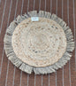 Round woven mat with fringes on a striped fabric background